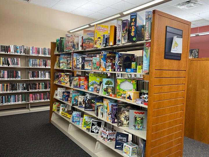 Bookshelf filled with board games, with another bookshelf of books visible behind it.