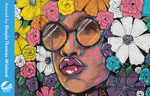 Colorful portrait of a woman wearing large round sunglasses surrounded by bright flowers.