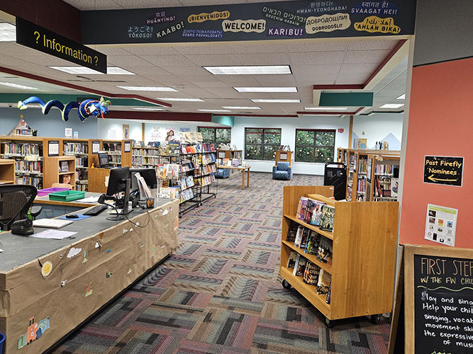 The Aboite Branch interior with shelves of books, a help desk, and welcoming signs in different languages.
