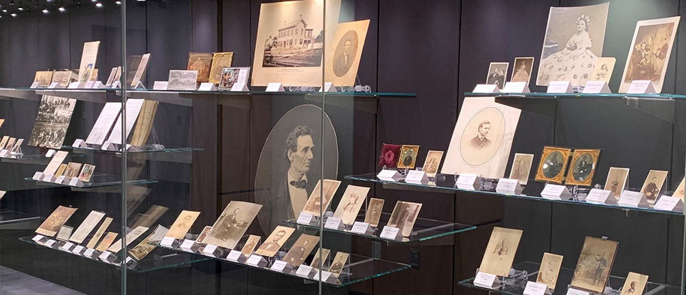 Display case showcasing historical documents and portraits in The Rolland Center for Lincoln Research.