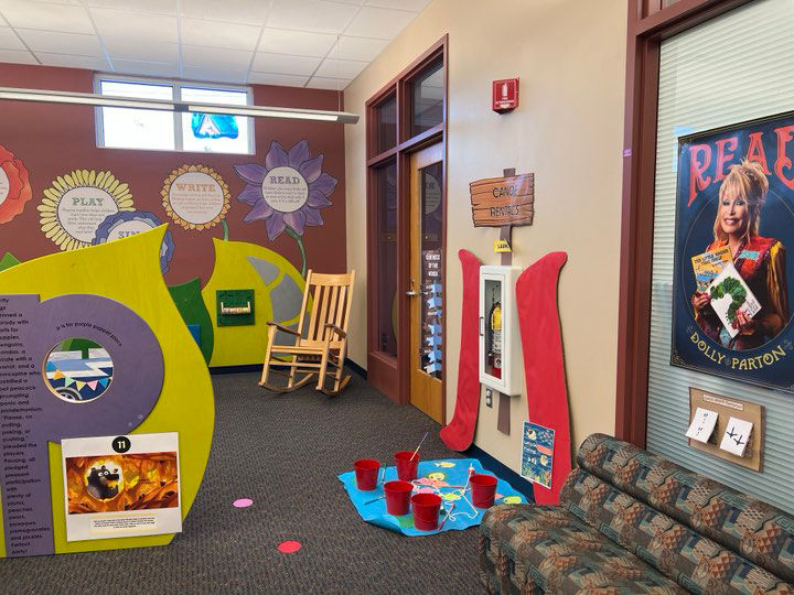 Library children’s area with colorful displays, a Dolly Parton poster, a rocking chair, and other decorations