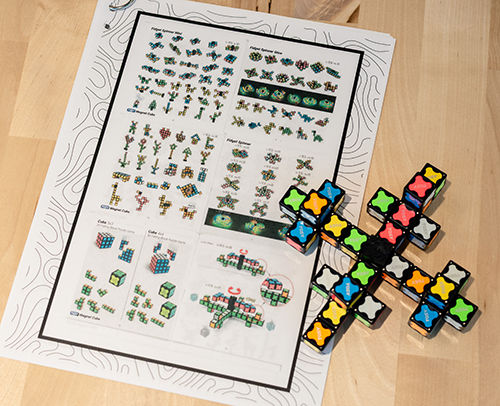 Magnetic cube puzzle pieces and instruction sheet showing geometric designs and building challenges.