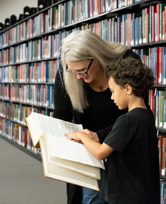 ACPL Staff Member helping a child look something up in a book