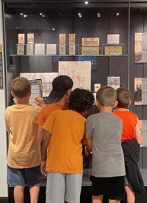 Children looking at display case with documents and artifacts in the Allen County Public Library.