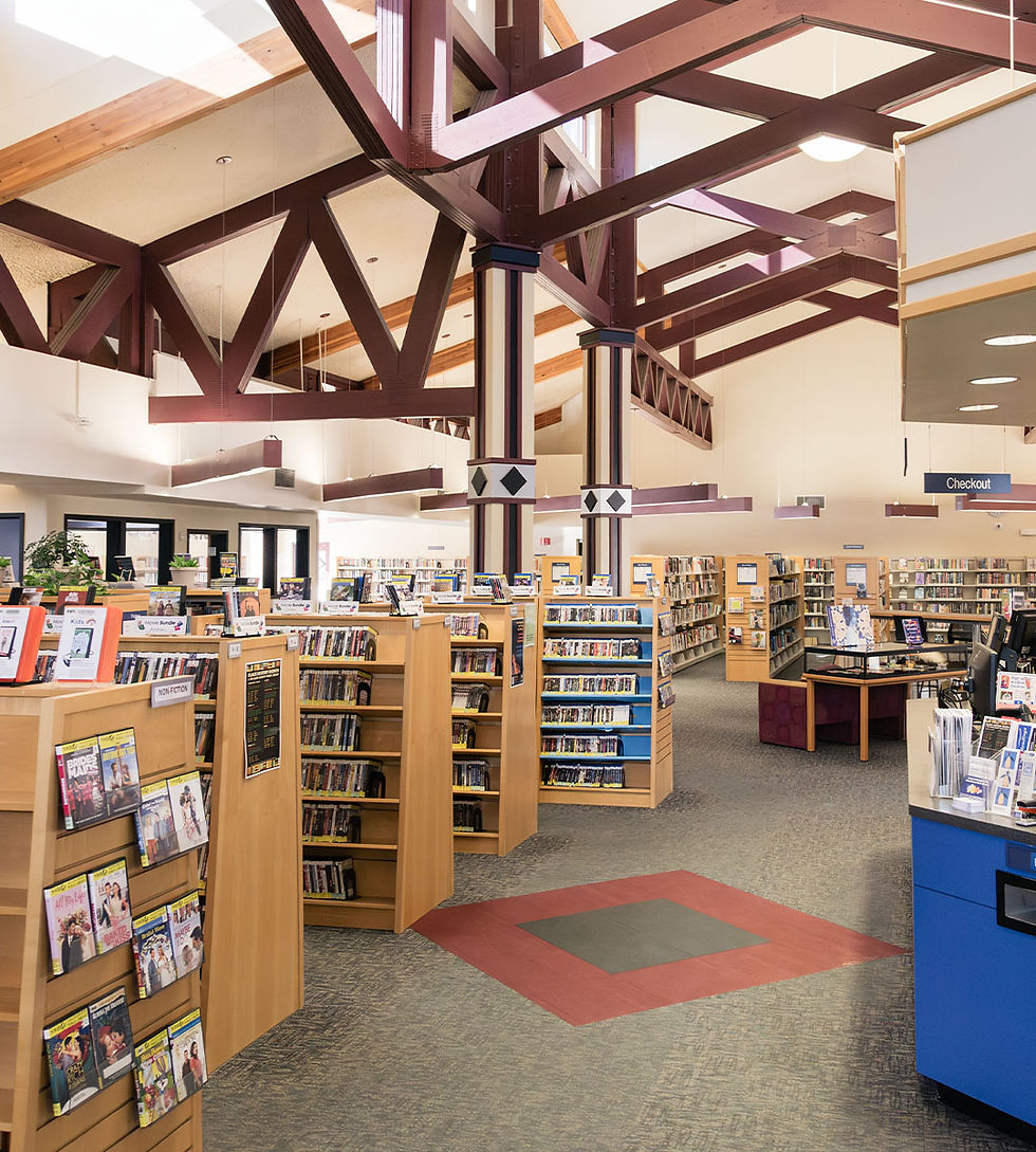 Library interior with dark red wooden beams, high ceilings, rows of bookshelves, and a checkout area.