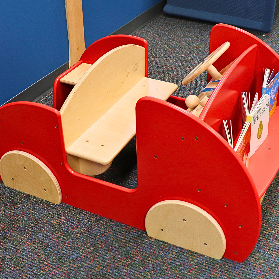 Close-up of a red wooden climb-on car designed for children.