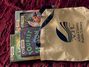 Various romance books coming out of an ACPL tote bag.