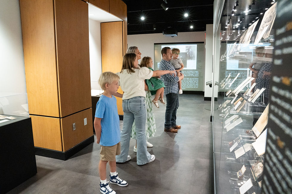 Family viewing an exhibit in a museum with displays, education, and Allen County Public Library.