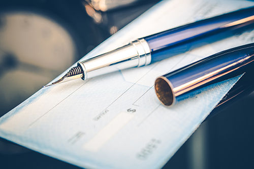 Pluma estilográfica sobre cheque en blanco listo para la firma y transacción financiera