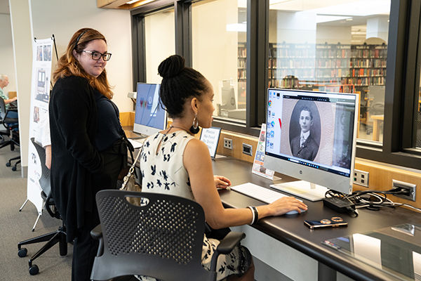Una bibliotecaria ayuda a una usuaria a investigar la historia de su familia en una computadora en el Centro de Genealogía.