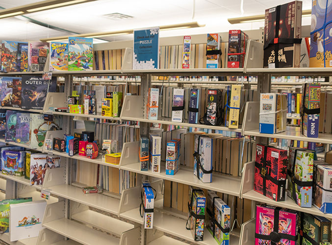 Los estantes de la biblioteca están repletos de diversos juegos de mesa en coloridas cajas.