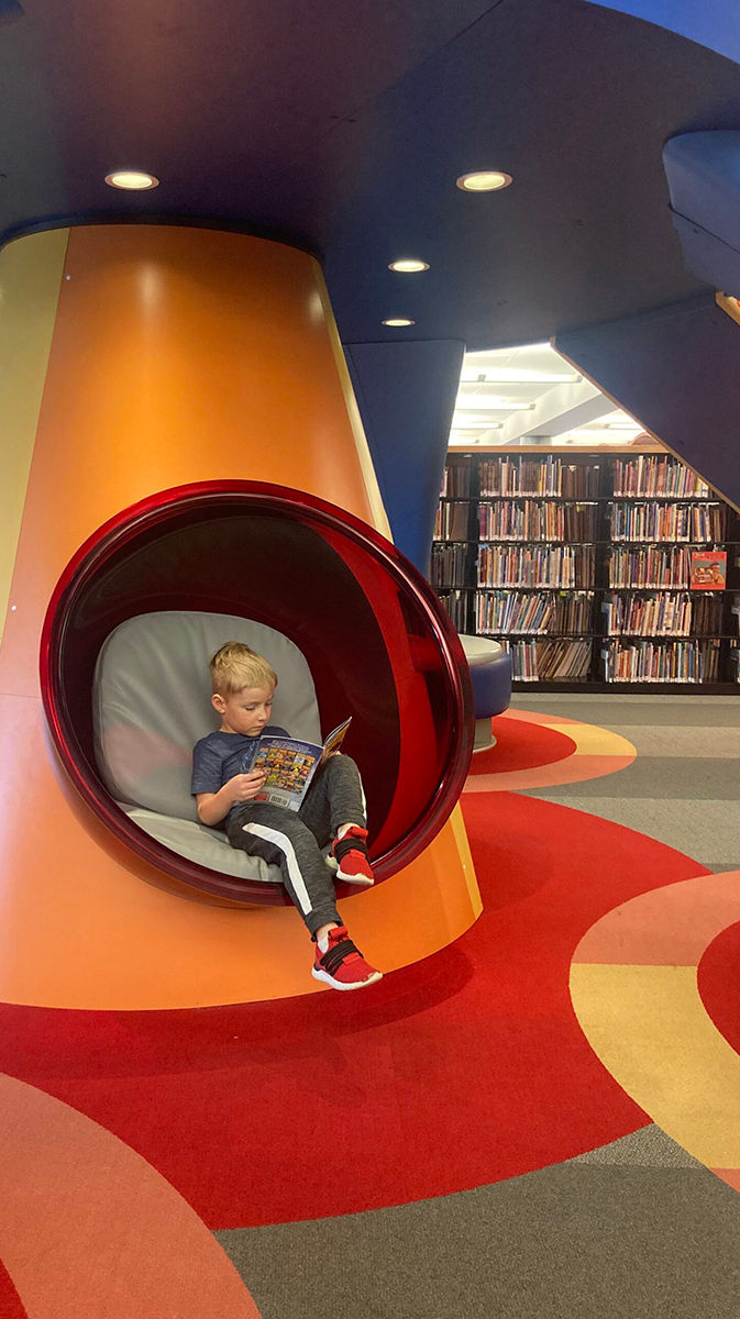 Un niño pequeño lee en una colorida cabina en la Biblioteca Pública del Condado de Allen.