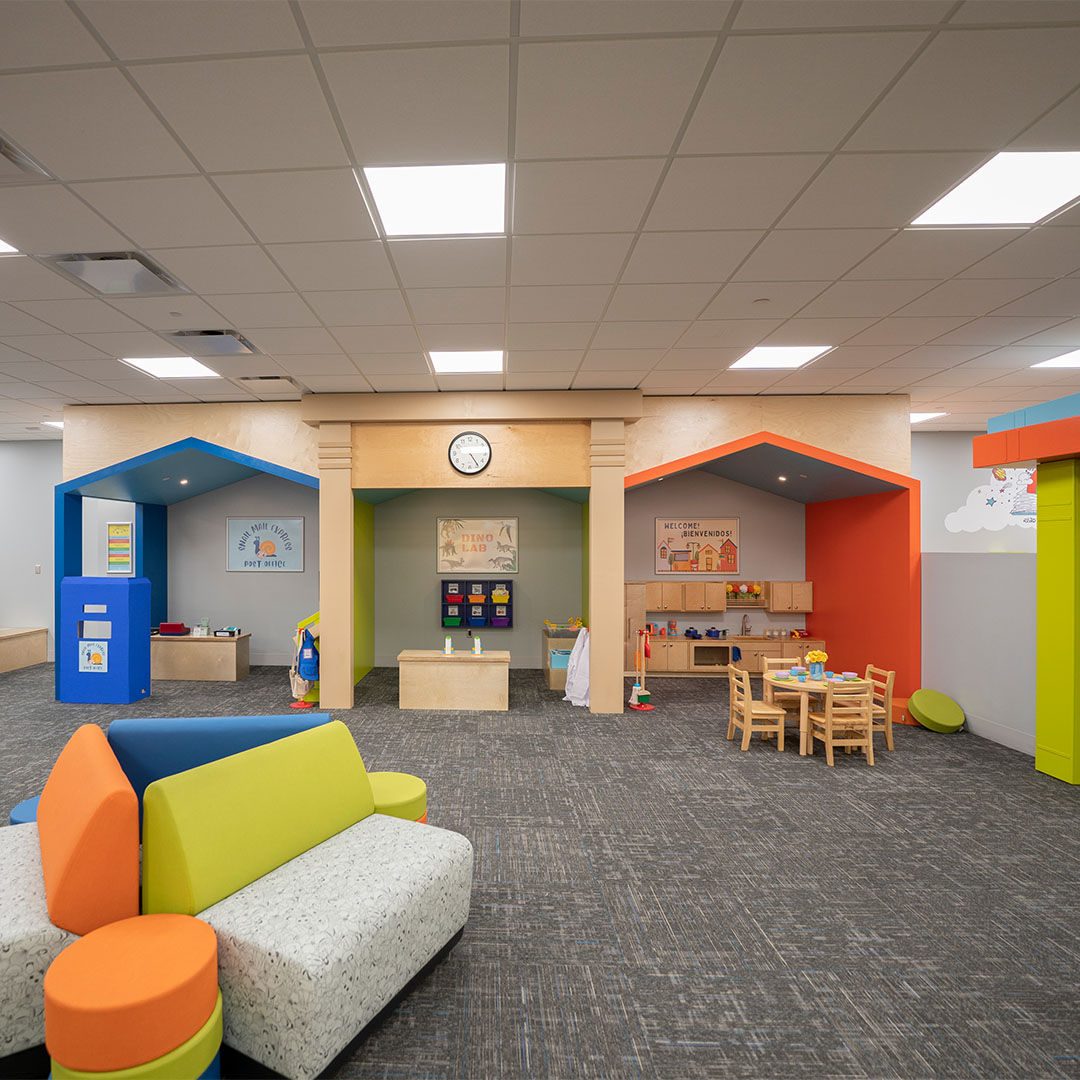 A spacious, colorful Storyscape area with house-shaped play areas, vibrant furniture, and educational toys.