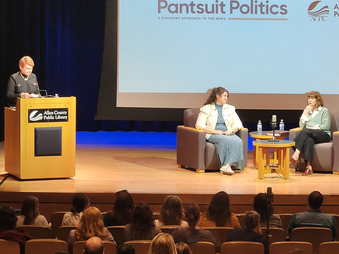 Pant Suit Politics podcast hosts on stage in the theater of the library.