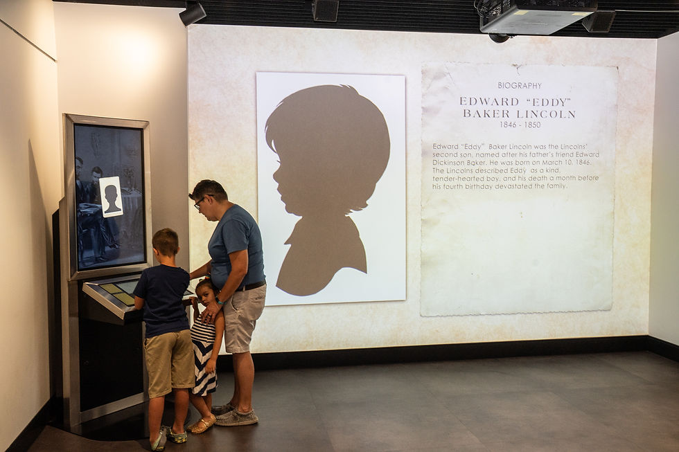 Una mujer y sus dos hijos pequeños observan una exhibición interactiva en el Centro Rolland para la investigación de Lincoln.