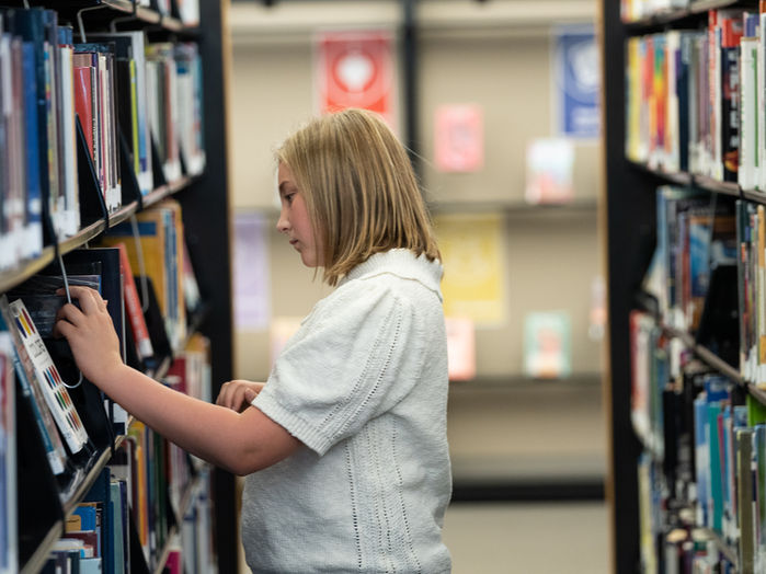 A young patron browses books in the library.