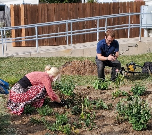 Two people gardening together; planting in a garden bed outdoors.